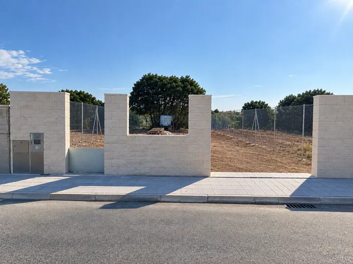 Muro con acabado en piedra, pilares y valla perimetral terminados